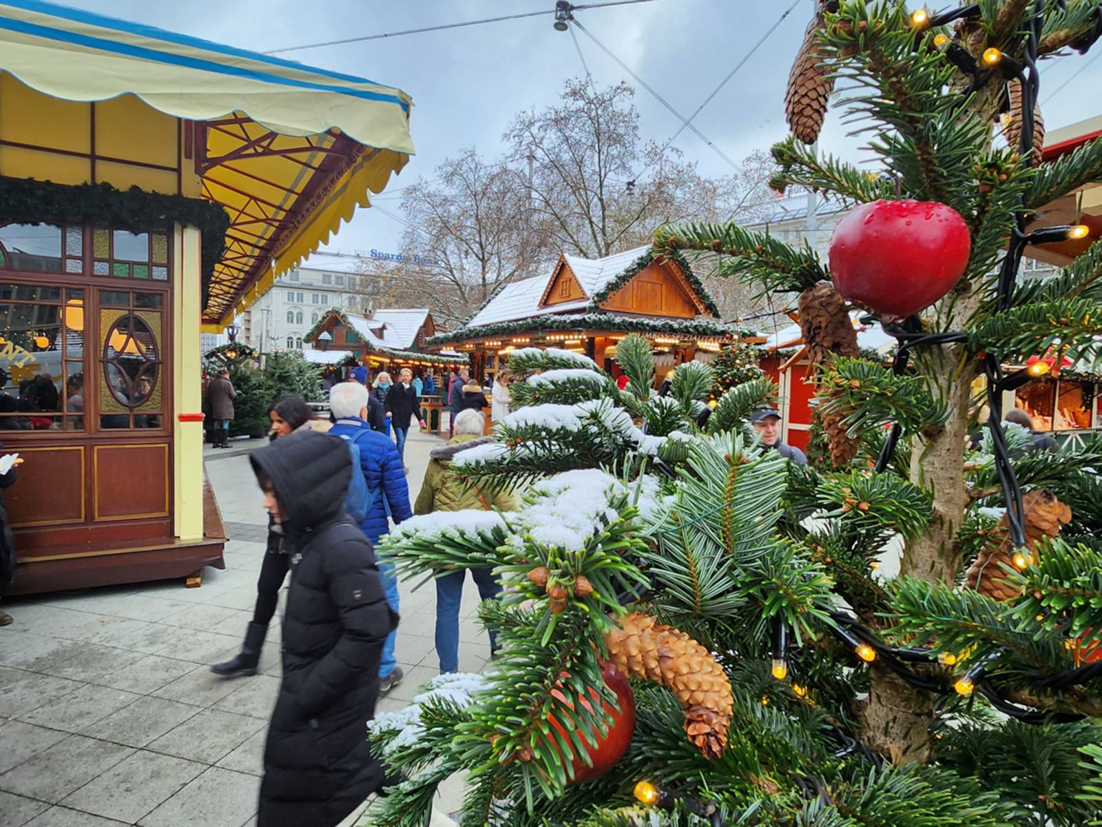 Weihnachtsmarktbuden und Tanne mit Dekoration