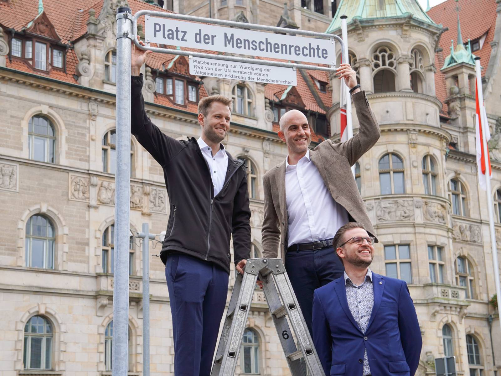 Drei Männer an einem Schild.