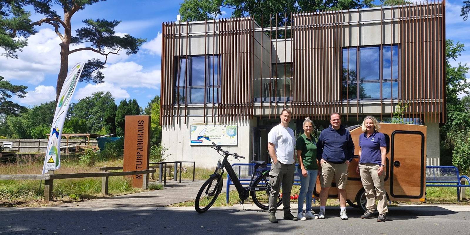 Vier Personen und ein Fahrrad mit Anhänger vor dem Naturparkhaus