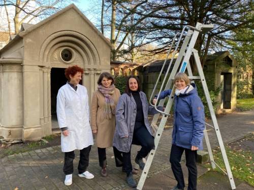 Vier Personen vor einem Mausoleum.