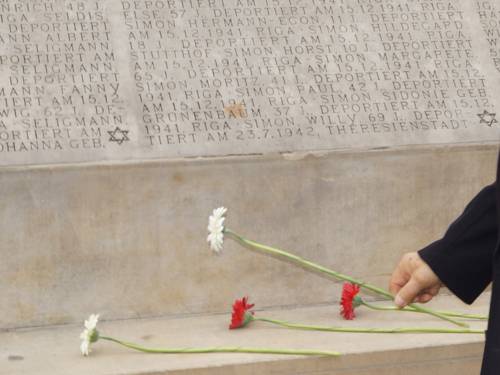 Two white and two red gerberas at the bottom of the Holocaust Memorial listing the names of the dead