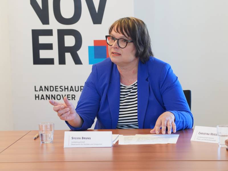 Eine Frau sitzt an einem Tisch und spricht.