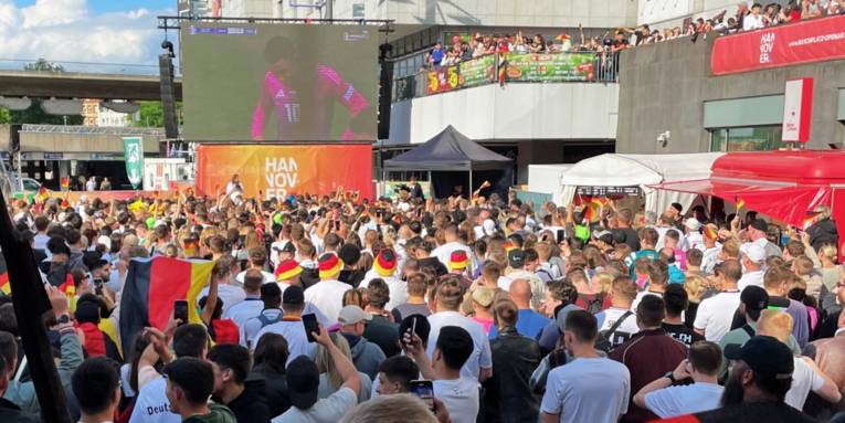 Zahlreiche Menschen auf einem Platz schauen das Deutschland-Spiel.