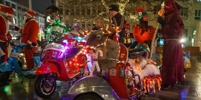 Weihnachtlich geschmücket Motorroller und Menschen verkleidet als Weihnachtsmann oder Wichtel am Kröpcke.