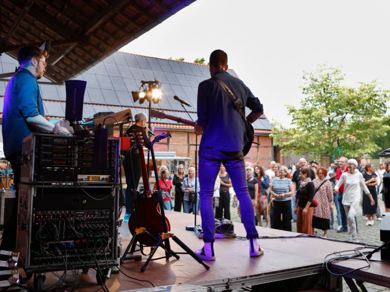 Zwei Musiker und eine Musikerin treten auf einer Bühne auf.