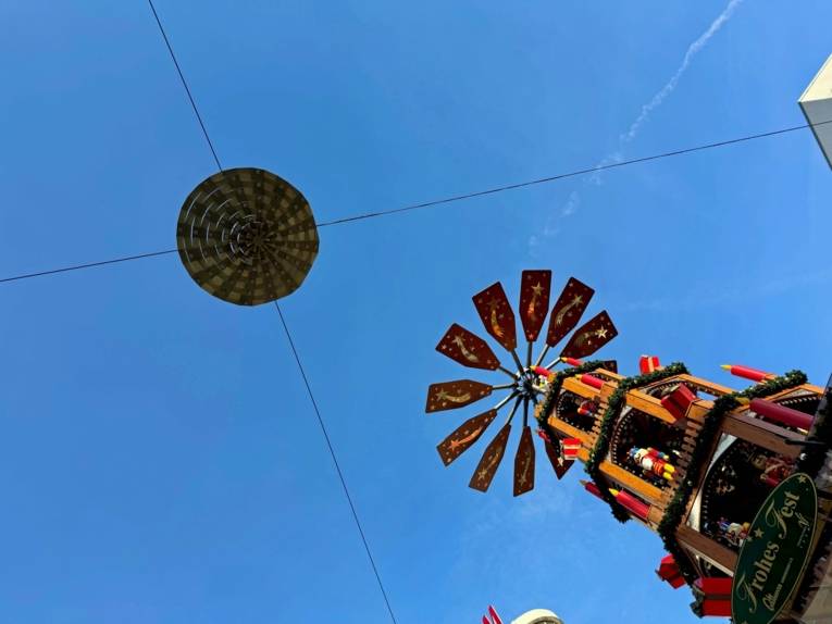 Eine Weihnachtspyramide ragt in den blauen Himmel.