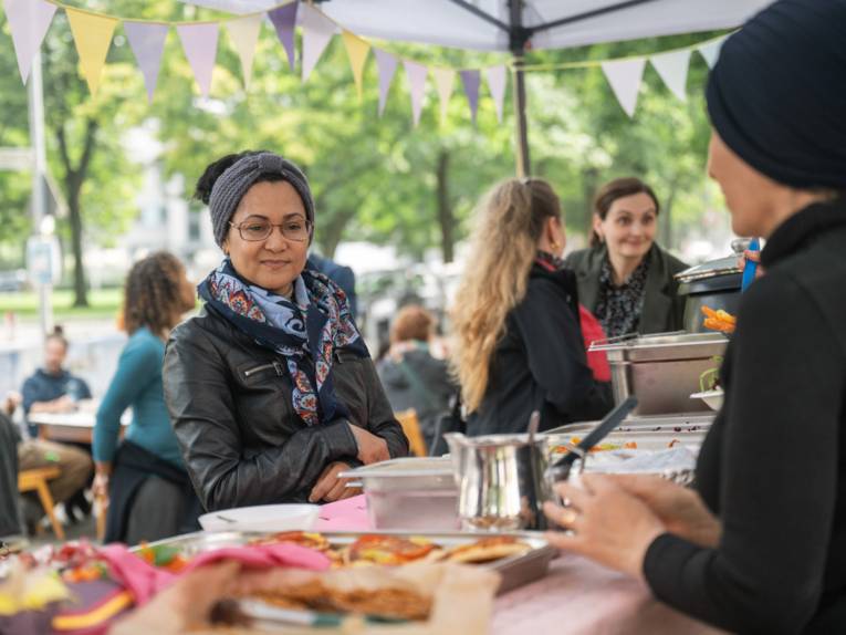 Eine Frau steht vor einem Tisch mit verschiedenen Gerichten und schaut sie sich an.