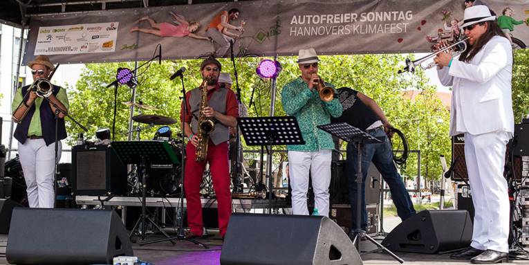 Drei Musiker mit Trompeten und ein Musiker mit Saxofon spielen auf der Bühne des Klimafestes in Hannover